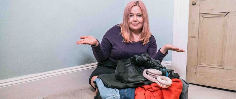 Kat with a suitcase and clothing items covering What to Pack When Moving to the UK