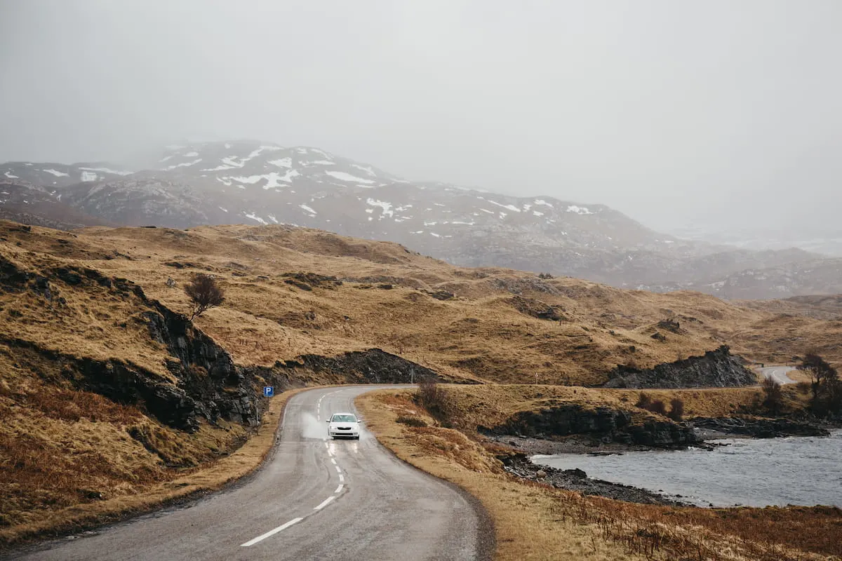 Unidentified car driving on a road going through Scottish Highlands near Lochinver