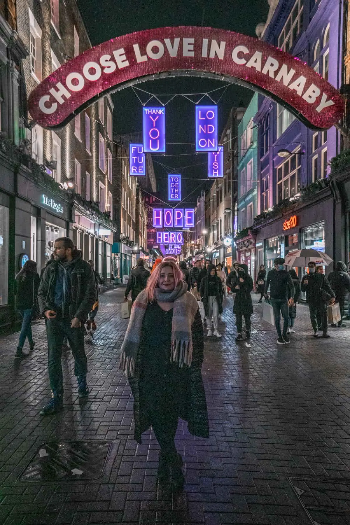 Kat standing in front of the choose love in Carnaby Christmas lights