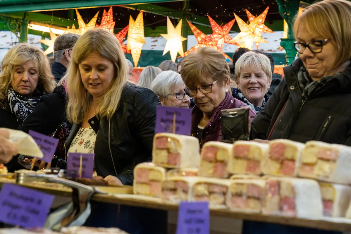 Women Shoppers looking at cakes on a stand at a Christmas Market in Harrogate, England Credit_Steve Gill