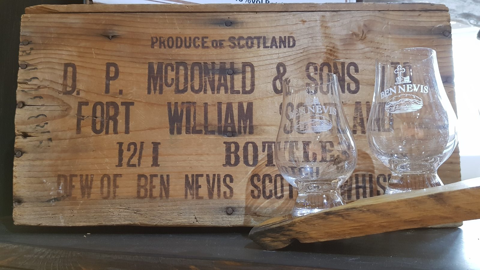 Stencilled Dew of Ben Nevis whisky crate and two Glencairn tasting glasses at the Fort William distillery.