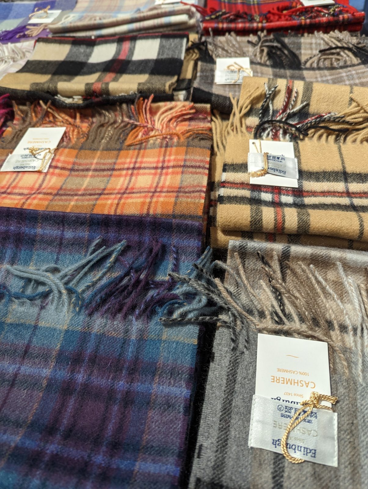Folded 100% cashmere tartan scarves stacked in an Edinburgh shop.