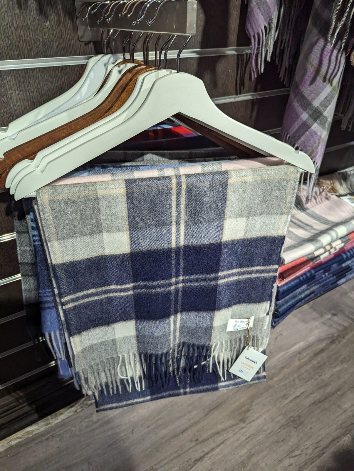 Blue and grey check 100% cashmere scarf hanging in an Edinburgh shop, tagged at £79.