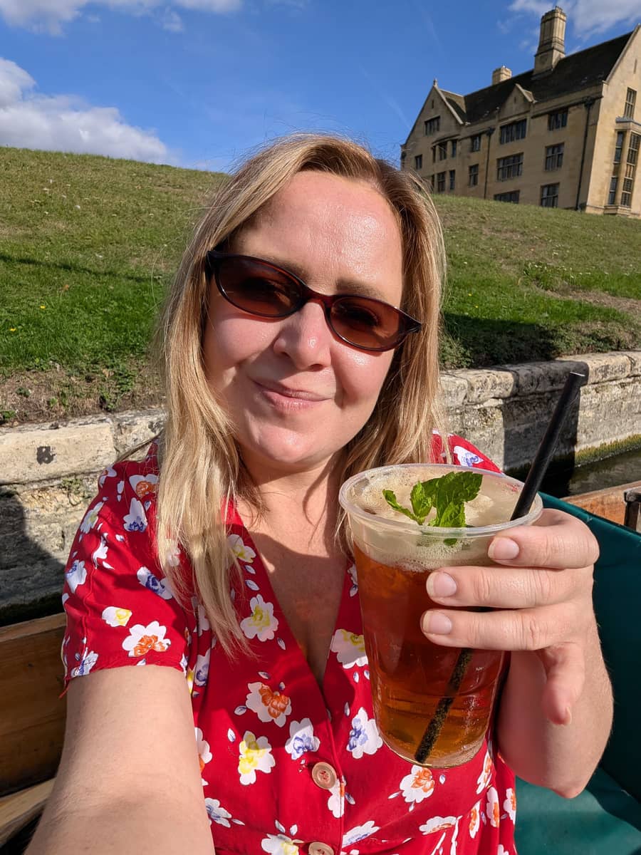 Kat on a punt on the River Cam with a Pimm's, the Backs behind her