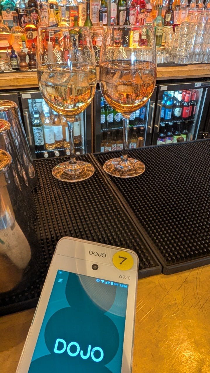 A card machine sitting on a bar next to two glasses of wine