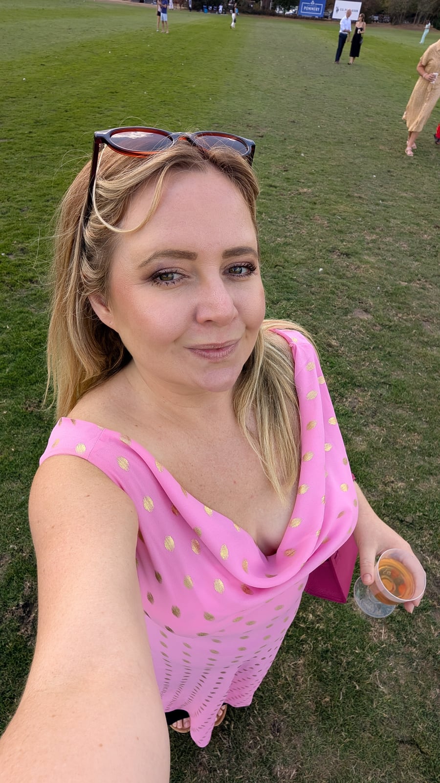 Kat on the picnic lawn at Ham Polo Club in a pink dress, glass in hand