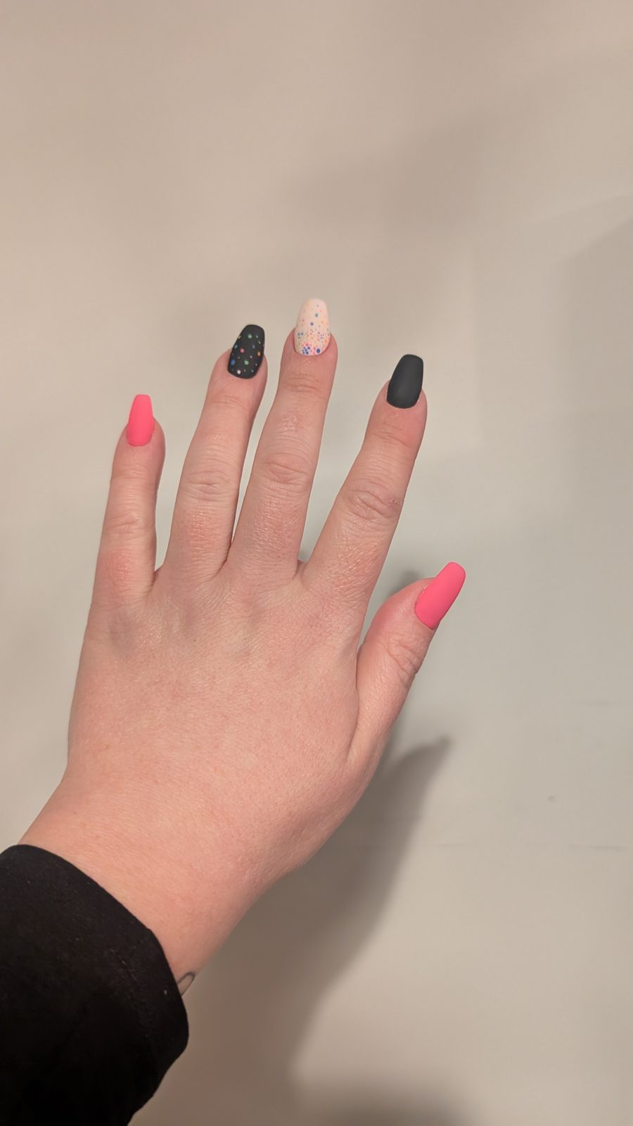 Matte black and neon pink coffin nails with a confetti accent nail