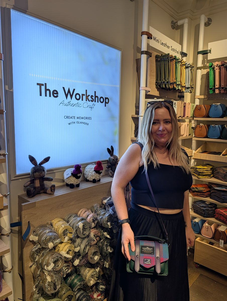 Kat with her finished tartan Islander bag in front of The Workshop sign