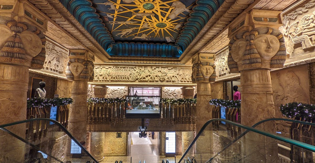 Egyptian-style escalator hall at Harrods with a blue and gold decorated ceiling